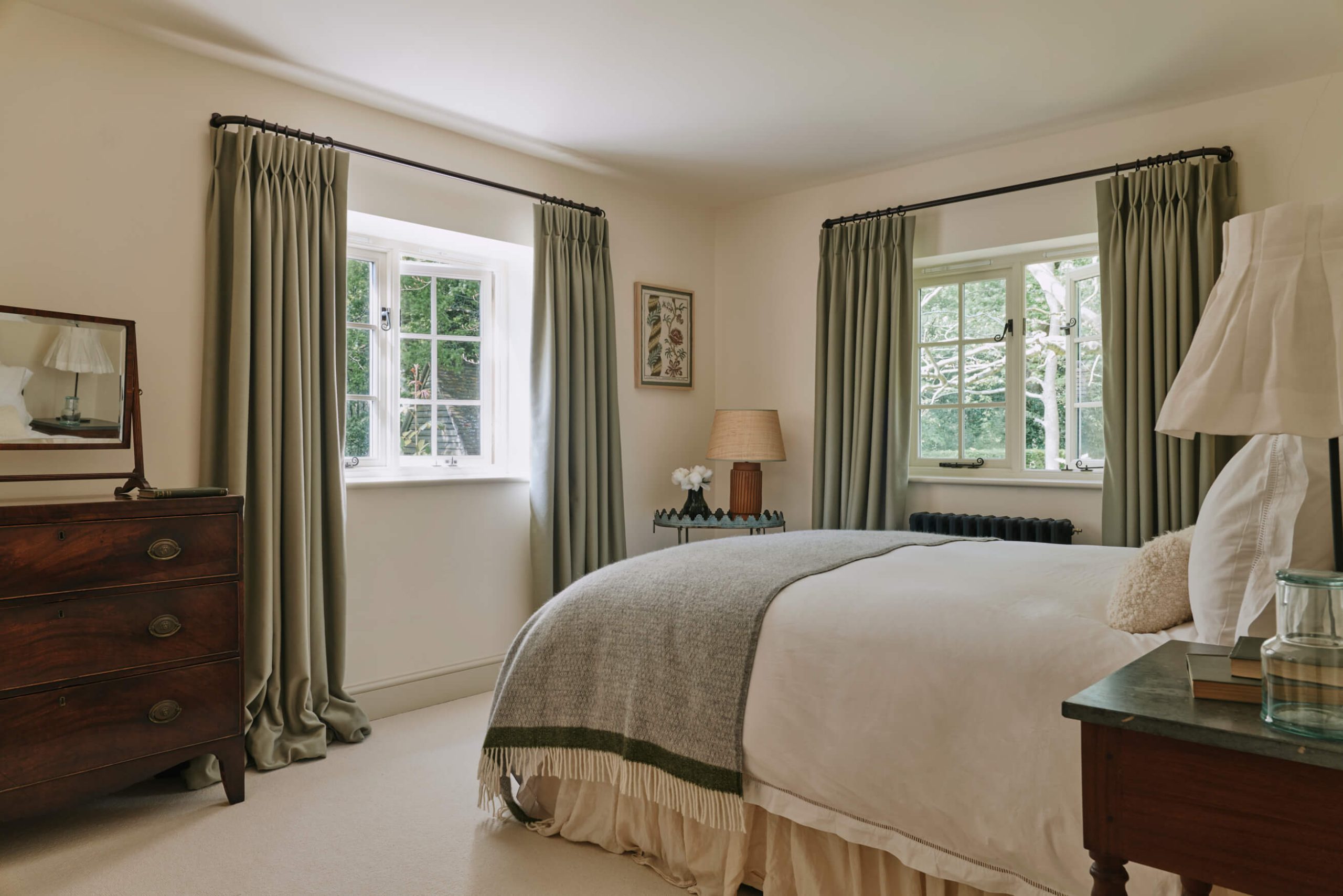 Looking into a bright bedroom with earthy green coloured curtains and bed spread. Interiors by Studio Squire