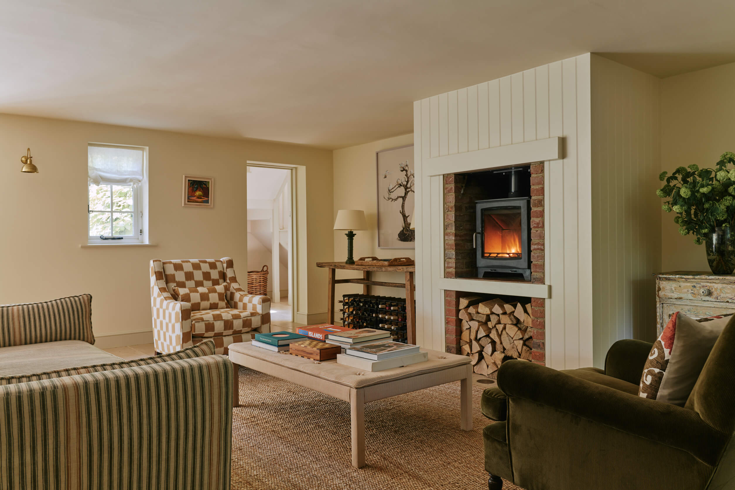 A cosy sitting room with log burner. Light cream colours designed by Studio Squire