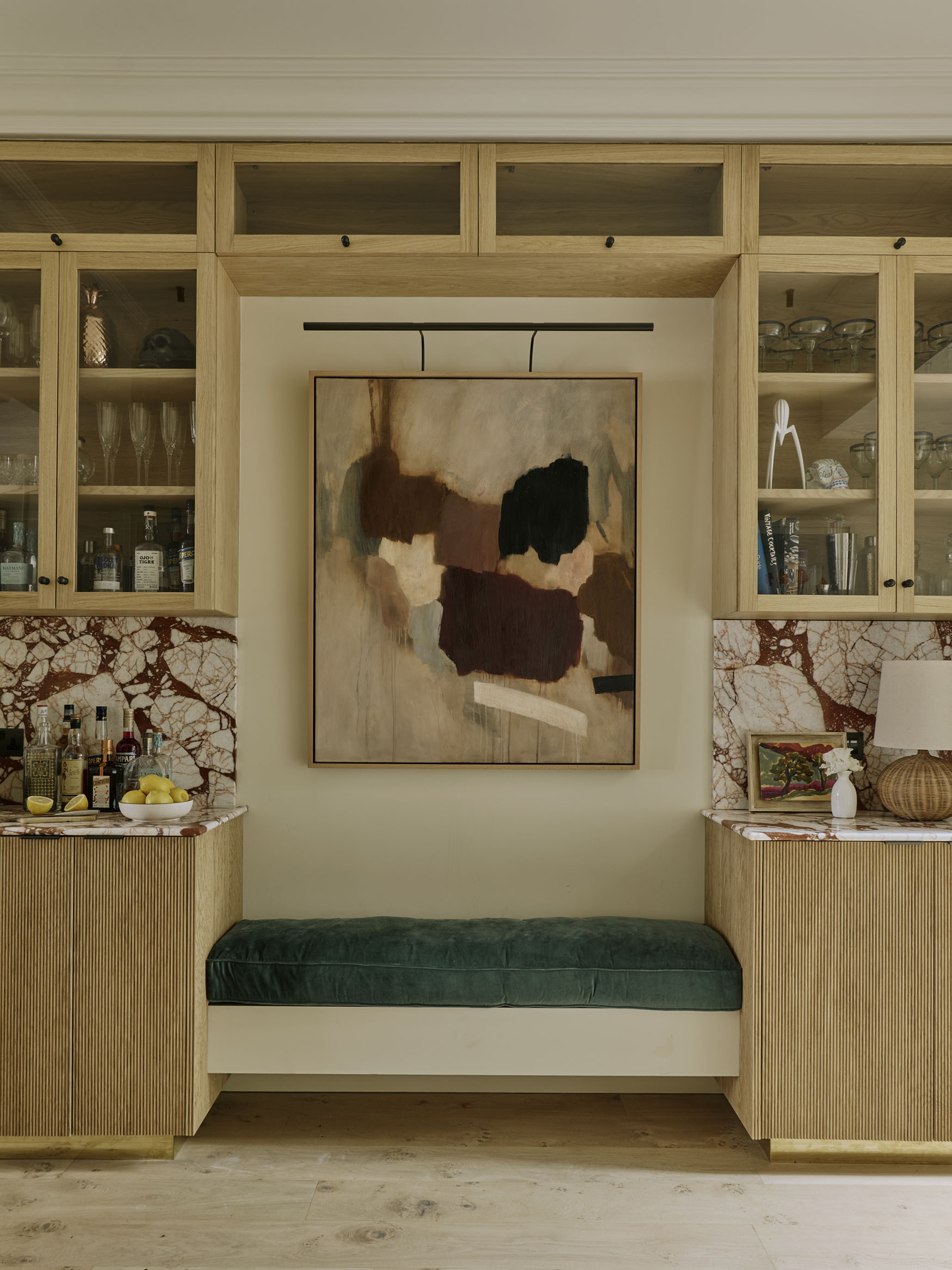 Bench seating between bookshelves with large painting, interior design by Studio Squire