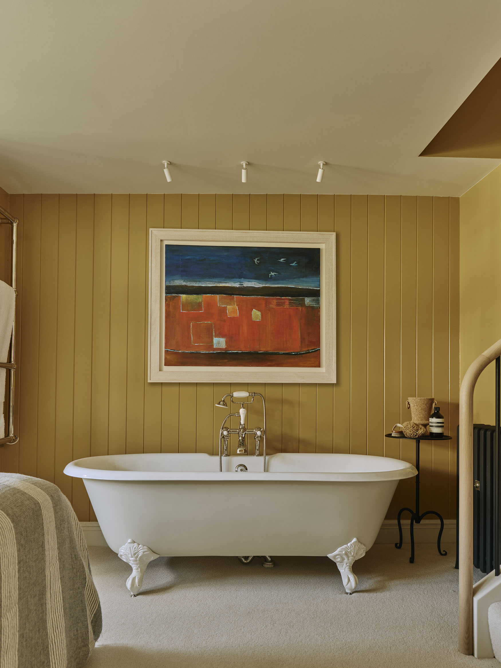 Roll top bath with large painting above, interior design by Studio Squire